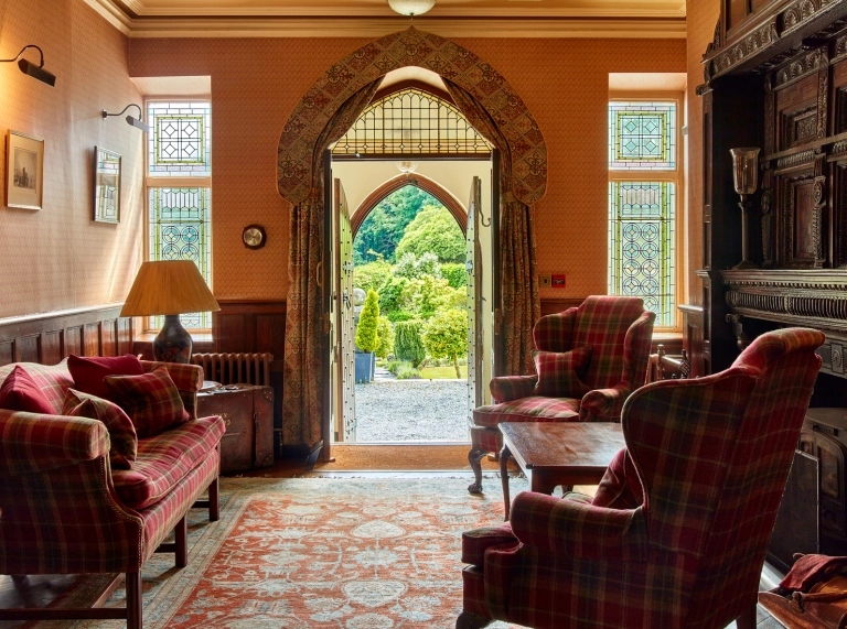 Sitting room in a hotel with doors leading out to lush green grounds.