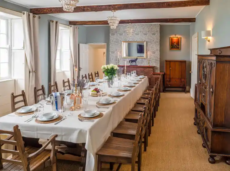 A room with a long dining table and chairs.
