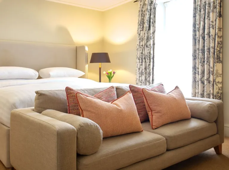 A bedroom suite with a sofa at the end of the bed.
