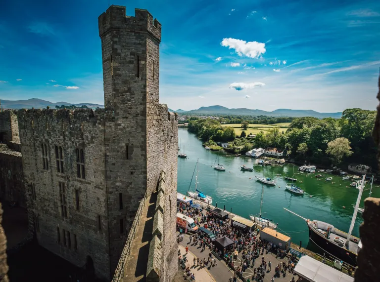 View of a castle turrent, food festival and harbour from the top of the castle wall.