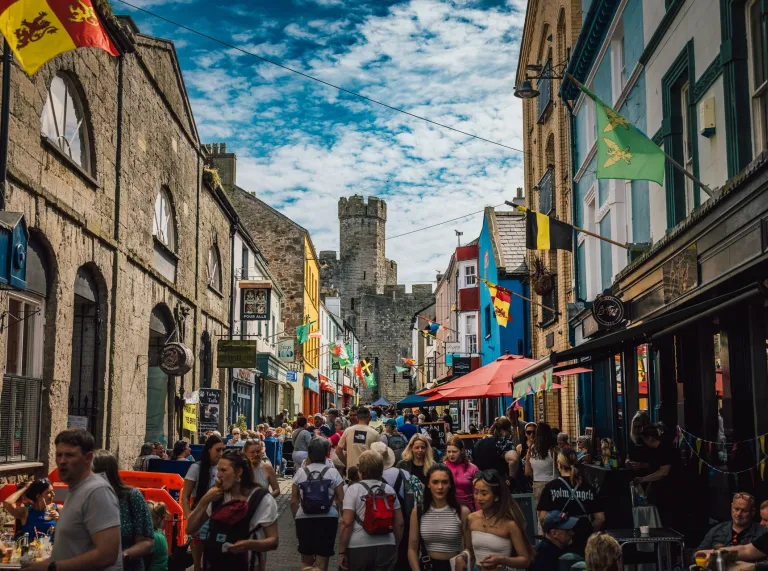 Food festival stalls in the streets of a market town with a castle beyond.
