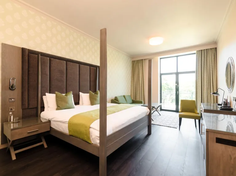 An executive bedroom in a hotel with workspace and sliding doors to a terrace.