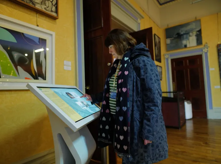 A lady using an interactive display in a museum.