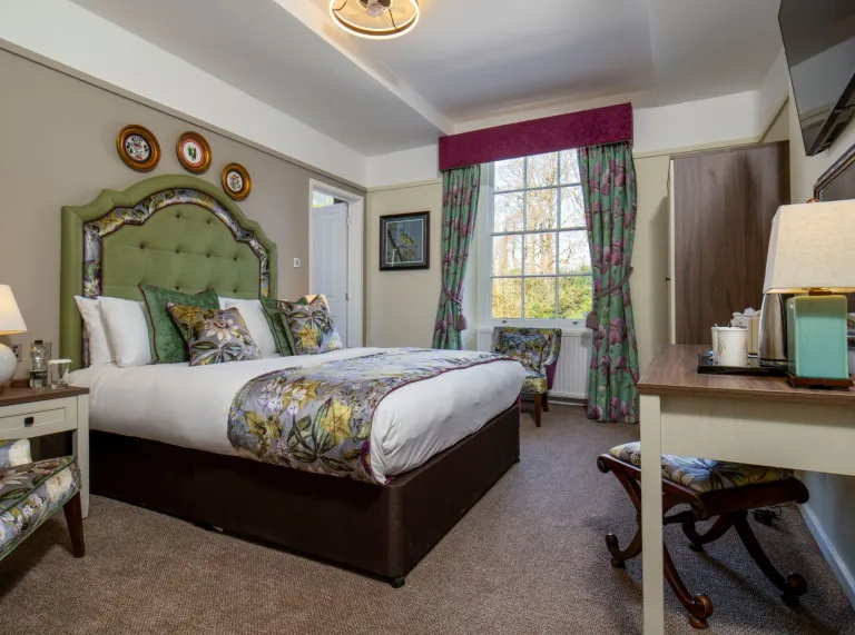 A bedroom suite in a hotel iwth floral furnishings.