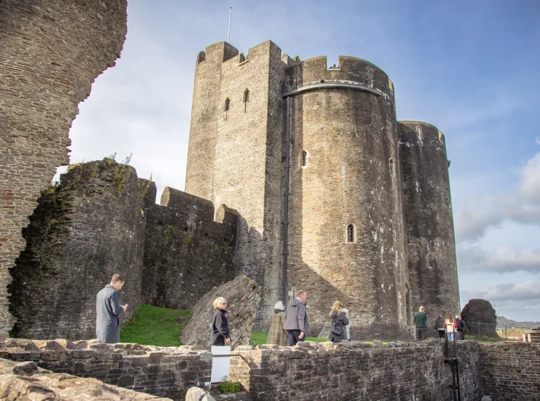 Group of people walking around a medieval castle on a sunny day.