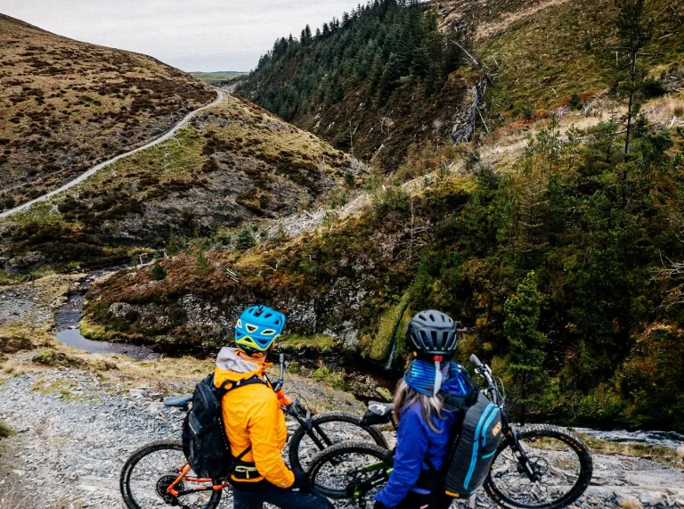 Cyclists looking at views of the mountains from cycling tracks.
