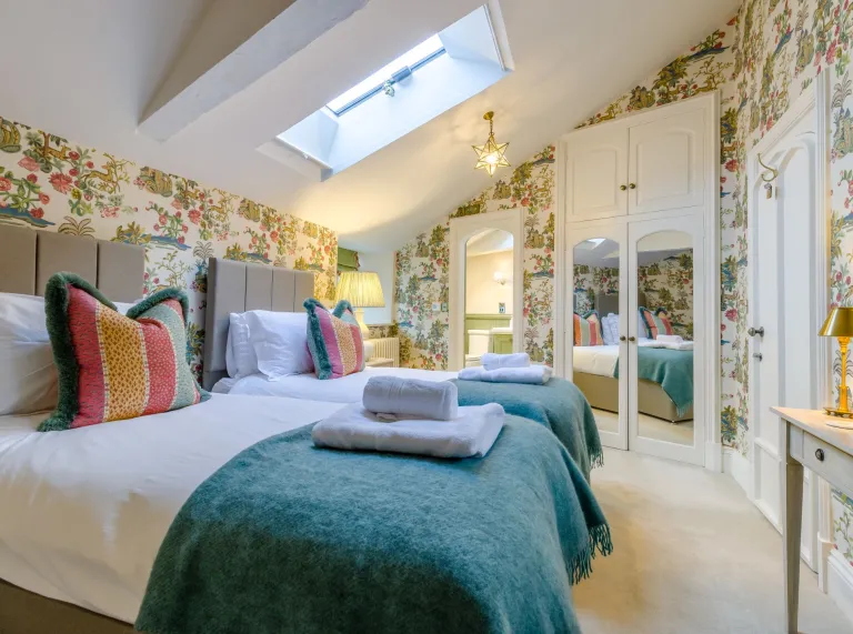 A bedroom in the eaves with ornate wallpaper and a skylight window.