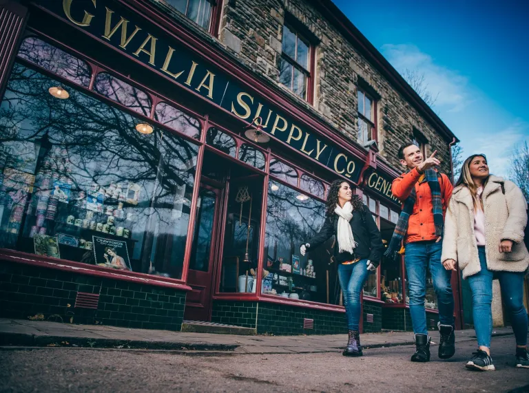 Group of people walking past an historic shop.