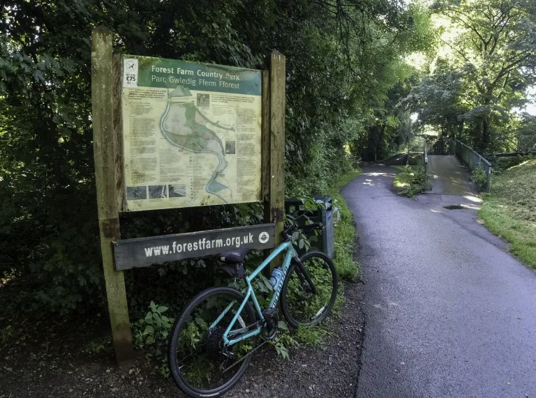 A mountain bike leaning against an information board in a park.