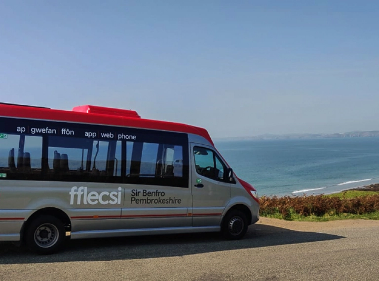 fflecsi minibus traveling along a coastal road.