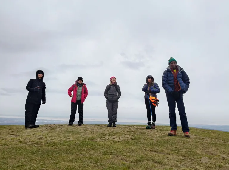 Group of people in warm coats and hats on a hilltop.