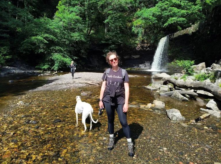 Lady and her dog by a waterfall.