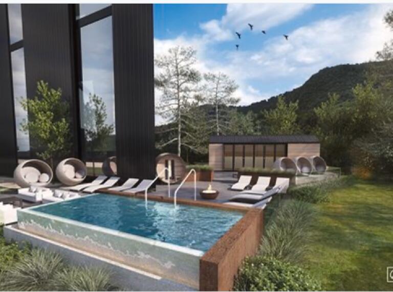 An outdoor spa with lounders and egg chairs surrounded by trees and mountains.