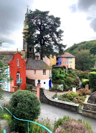 Colourful houses surrounded by garden and the church tower in Portmeirion italianate village.