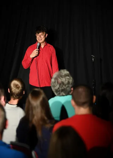 Phil Wang doing a stand up show in front of a crown of people at a comedy festival.