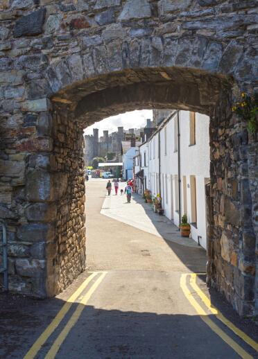 A view of Conwy castle and pretty houses of Conwy through an arch in the town wall.