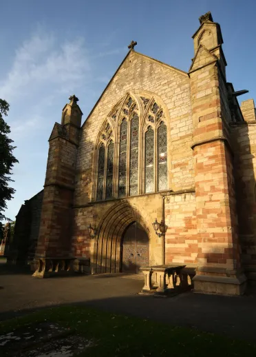 Exterior view of St Asaph Cathedral with the sun blazing against the brickwork.