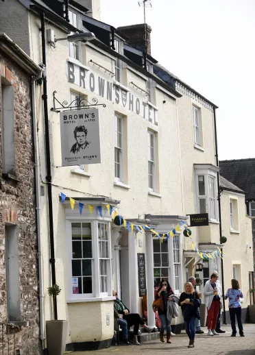 An external vew of Browns Hotel with a Dylan Thomas sign hanging outside.