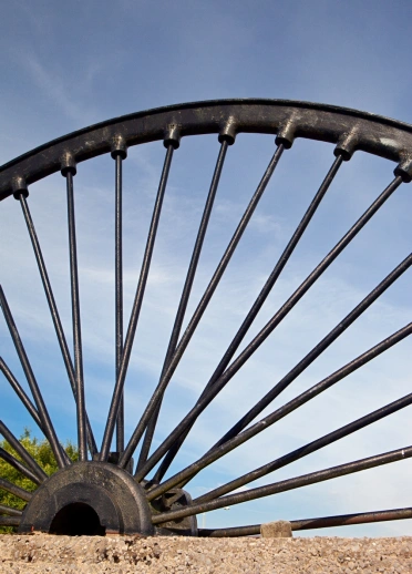 A large black winding wheel in an old colliery.