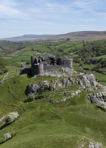 The ruins of a castle in the countryside on the edge of a cliff.