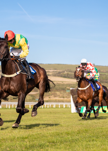 Jockeys riding their horses along the course on Race Evening at Ffos Las Racecourse.