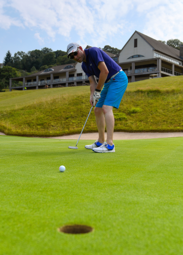 A golfer on the green putting his ball into the hole at Celtic Manor Golf Resort.