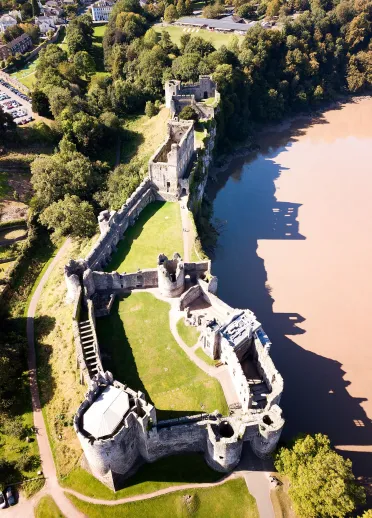 An aerial shot of Chepstow Castle with a shadowy reflection in the River Wye.