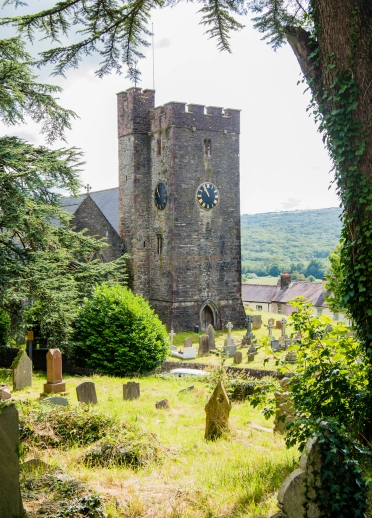 exterior of church with clock tower and countryside in background.