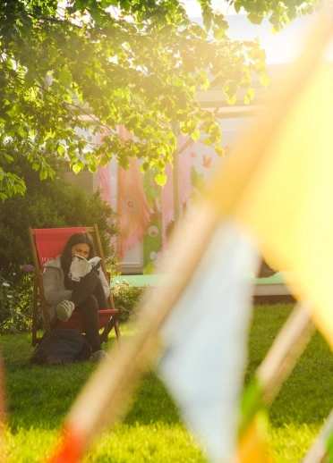 A reader in a deckchair on a grass field with festival banners in the foreground.