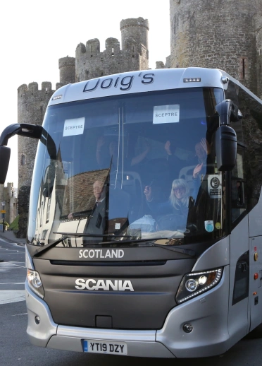 A coach parked up outside a castle.