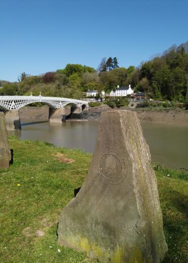Stones marking Offa's Dyke Path by a river and iron bridge.