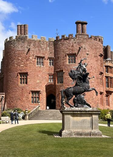 Statue of a horse and rider outside a castle.