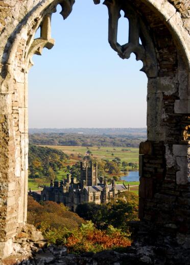 Views of a castle in a country park through an abbey window.