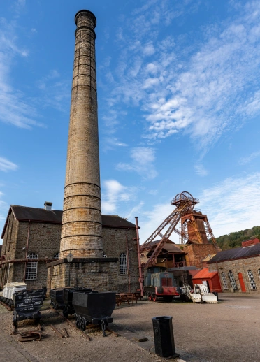 A chimney and winding wheel at a coal mining experience.