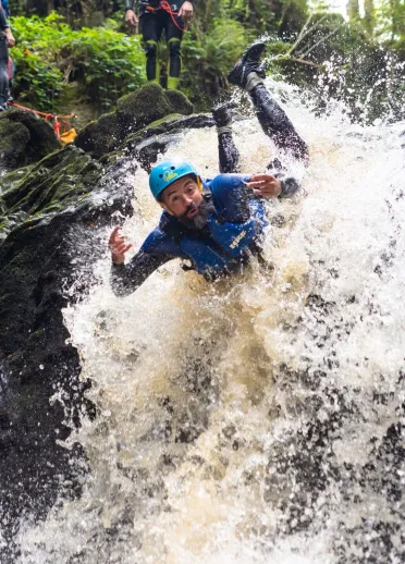 People wearing safety gear canyoning down a waterfall