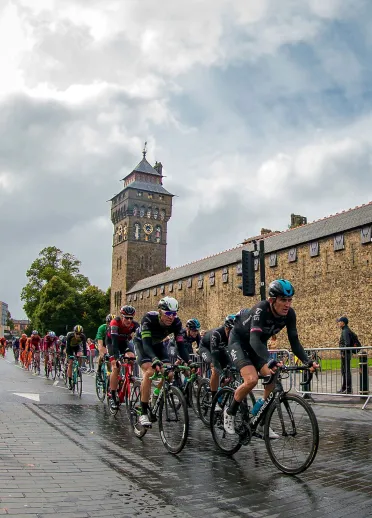 Group of competitive cyclists passing a castle in a city centre.