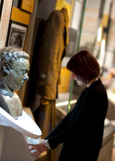 A bust of Dylan Thomas and people exploring exhibits at the Dylan Thomas Centre.