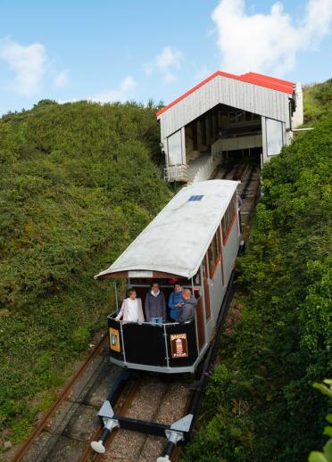 A railway carriage leaving the station shed decscending down a cliff.
