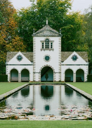 The summer house reflecting in the pool with water lillies at Bodnant Garden.