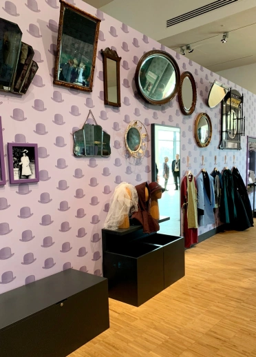 Old fashioned clothes, hats, mirrors and photos in a museum.