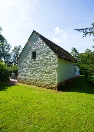 A white chapel on a grassy lawn on a sunny day.