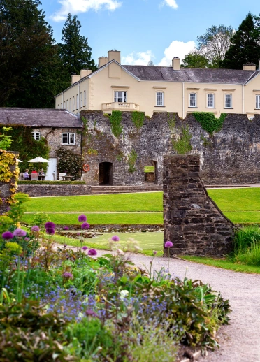 A grand walled mansion amongst colourful gardens.