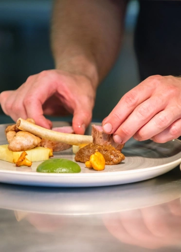 A chef preparing food on a plate