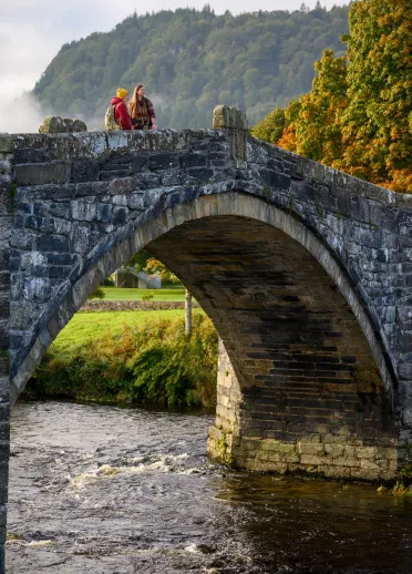 A couple on a stone bridge crossing the river.