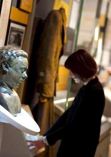 A bust of Dylan Thomas and people exploring exhibits at the Dylan Thomas Centre.
