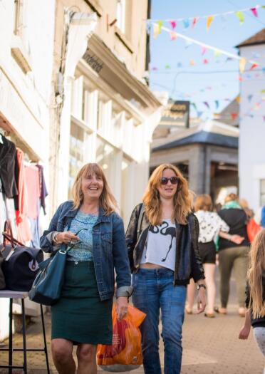 Shoppers walking down a street in a book town lined with bunting.