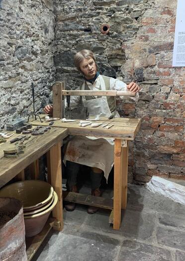 A model of a man making pipes in a display.