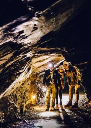 A group of people wearing safety gear in an underground slate cavern.