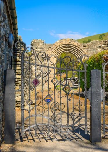 The ruins of an abbey seen through an iron gate.