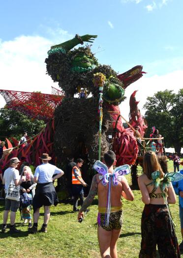 Giant green man and red dragon sculptures amongst party revellers at Green Man Festival.
